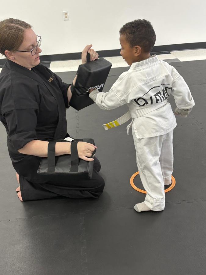 Mrs. Kena coaching a young student through a striking drill at Legacy Martial Arts